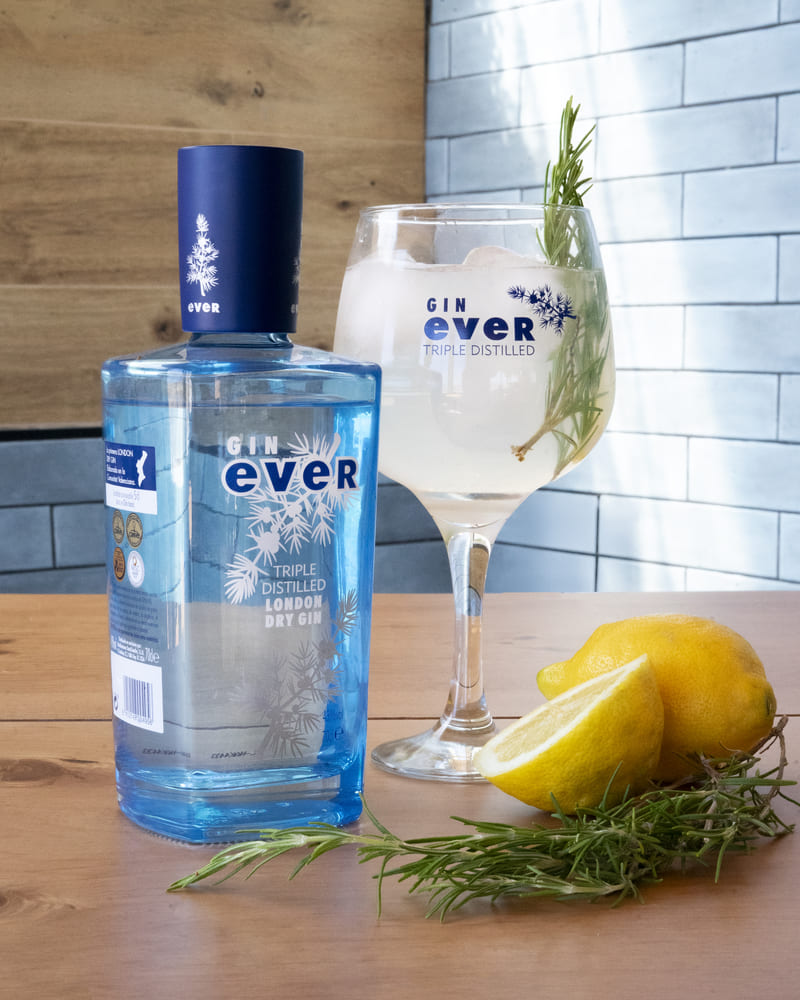 Botella de Gin Ever London Dry Gin con copa de balón, romero y limón